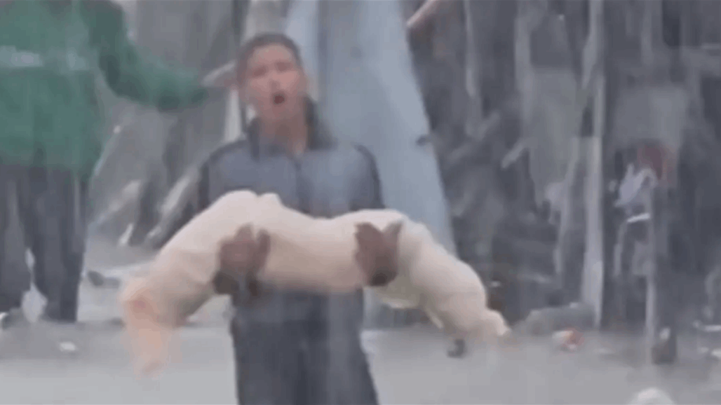 فتى فلسطيني يحمل جثة صغيرة وسط السيول في غزة (فيديو)